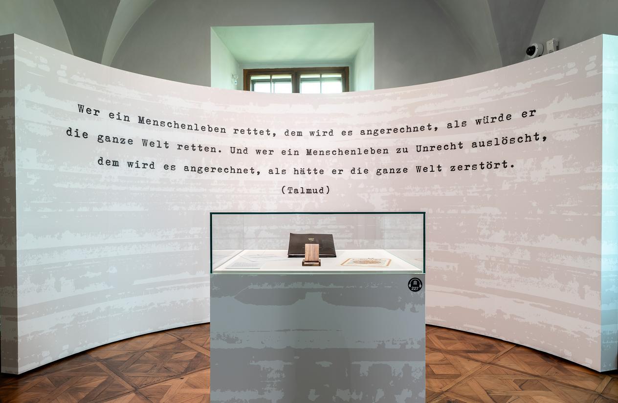 Hinter einer Ausstellungsvitrine ist auf der Wand folgendes Zitat aus dem Talmud zu lesen - Wer ein Menschenleben rettet, dem wird es angerechnet, als würde er die ganze Welt retten. Und wer ein Menschenleben zu Unrecht auslöscht, dem wird es angerechnet, als hätte er die ganze Welt zerstört. 
