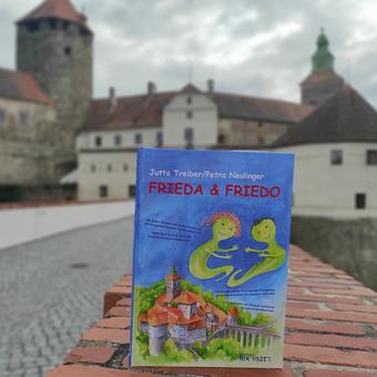 Das Buch Frieda und Friedo von Jutta Treiber und Petra Neulinger ist auf einer Mauer vor der Friedensburg Schlaining aufgestellt.