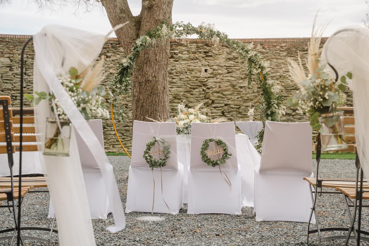 Stühle und Blumen-Dekoration für eine Hochzeit im Freien